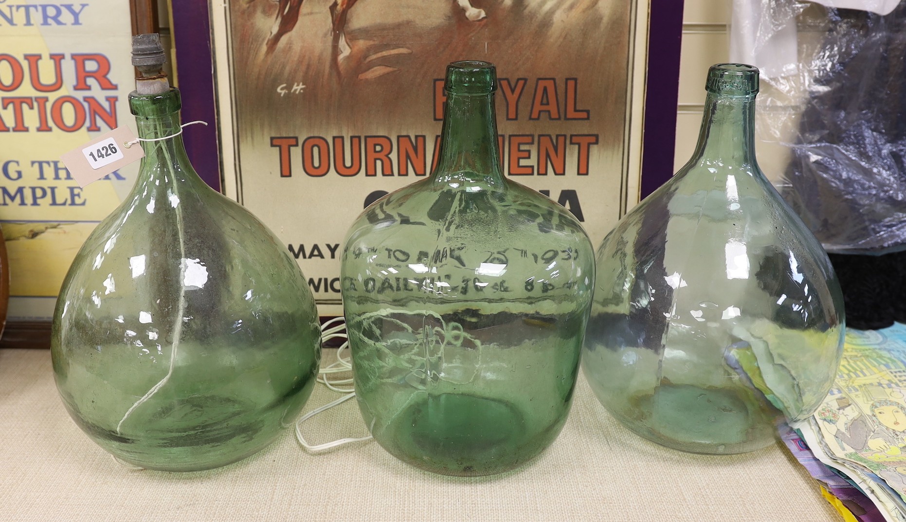 Three green glass carboys, one converted to a lamp - tallest 40cm